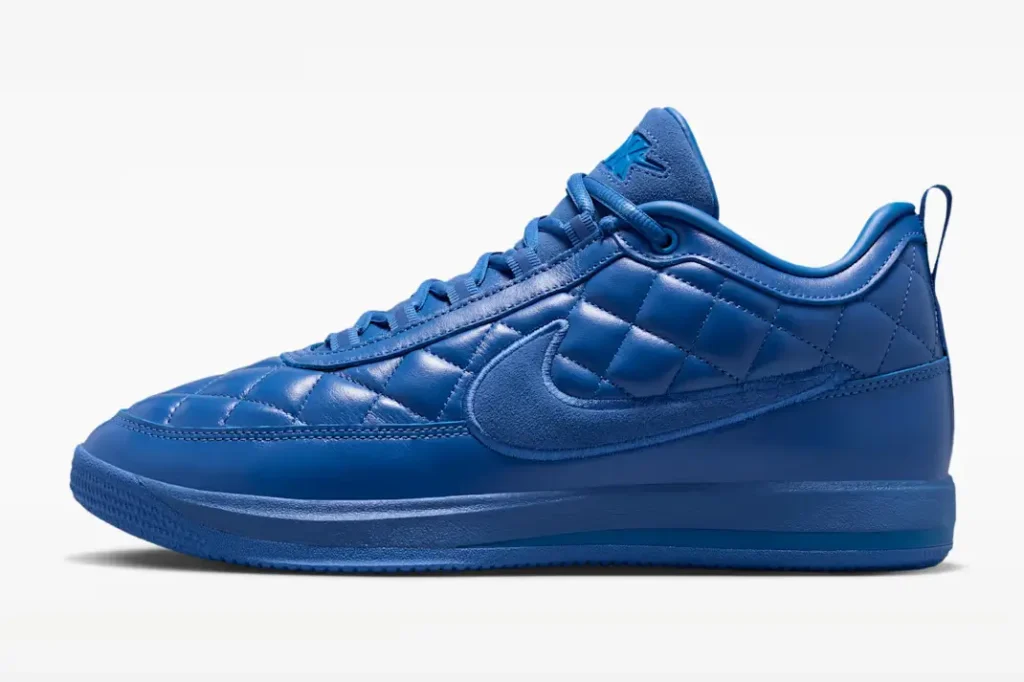 Side profile of a blue Nike shoe with diamond-quilt leather, oversize tonal suede Swoosh and monochromatic blue sole