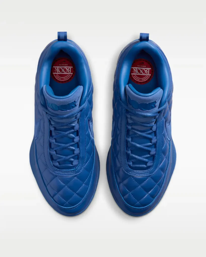 Top-down view of a pair of blue Nike shoe with quilted uppers, tonal laces and red BOOK graphics view on the insole