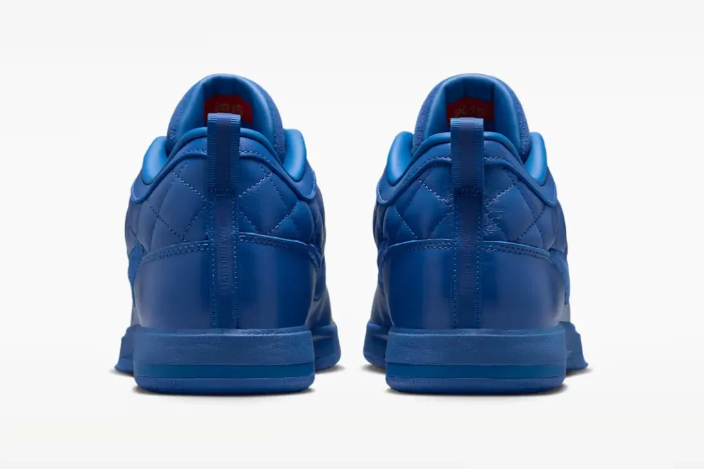 Rear view of a pair of blue Nike shoe highlight quilt heels, vertical pull tabs and match blue midsole