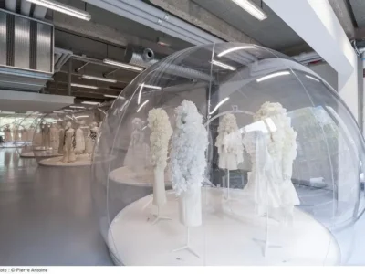 Comme des Garçons exhibition featuring white garments displayed inside large transparent dome
