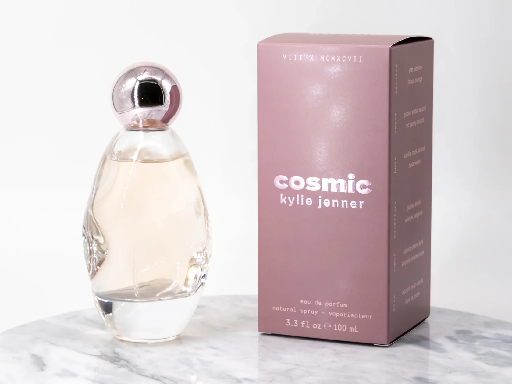 Kylie Jenner Cosmic perfume bottle and mauve box on a white marble surface
