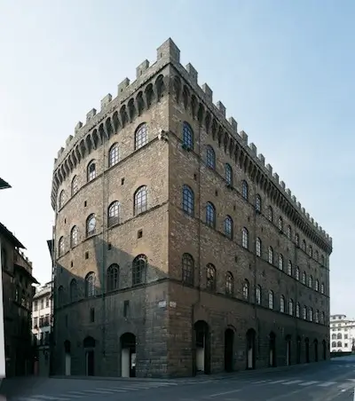 Exterior view of Palazzo Spini Feroni in Florence, Italy, showcasing its imposing medieval stone façade, crenellated roofline, arched windows, and fortress-like architecture, home to the Ferragamo headquarters and museum.