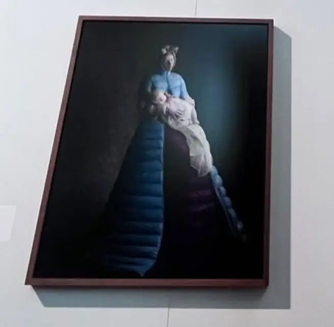 Framed Portrait Of A Woman In A Dramatic Blue Period Gown Holding A Figure Draped In Pale Fabric Against A Dark Background