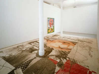 Contemporary gallery with a large abstract floor installation, white columns, and a hue frame artwork