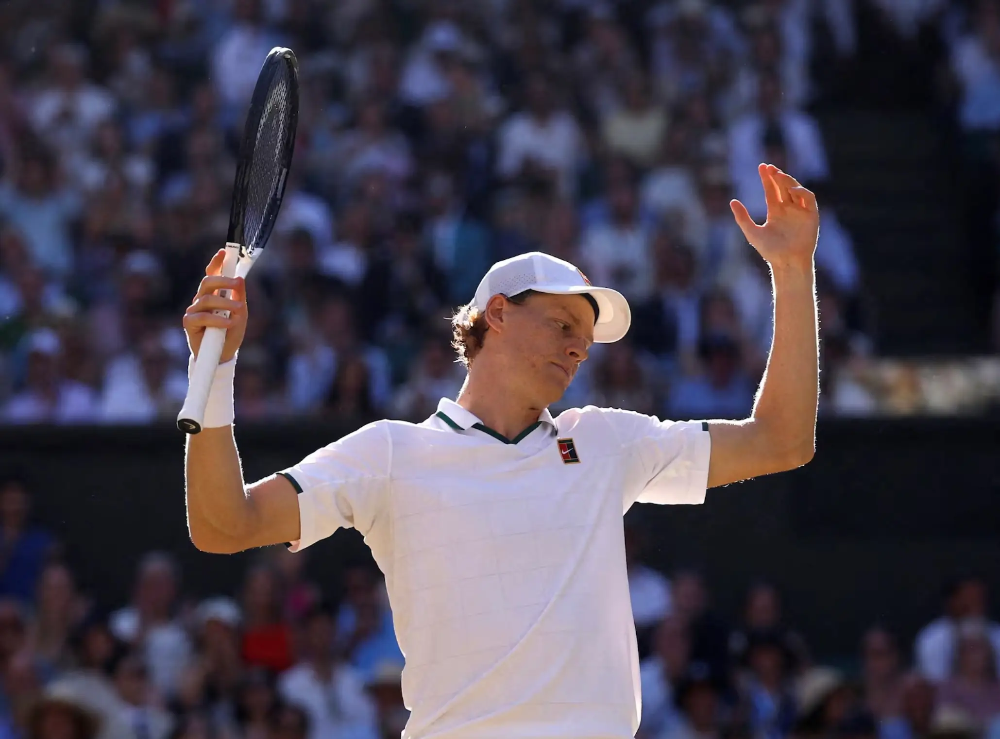 Tennis Player In White Raises His Racket During A Match On A Grass Court