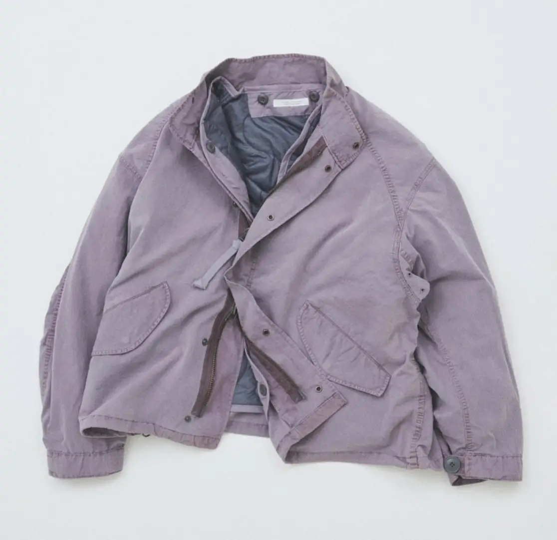 Light lavender garment-dyed utility jacket with a stand collar, concealed zip front, oversized flap pockets, and partially open construction revealing the interior lining.