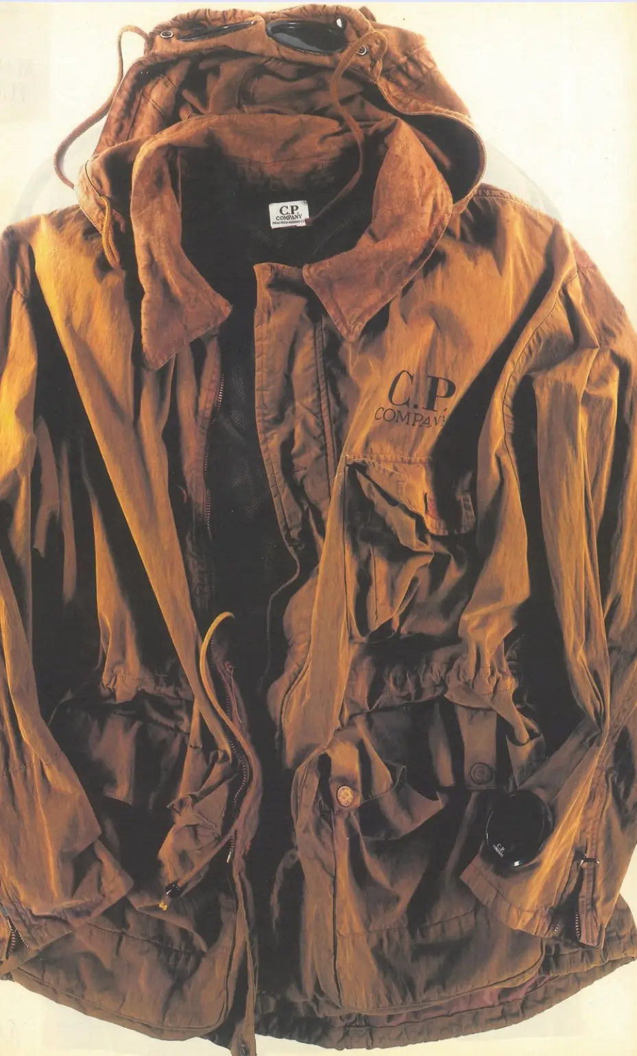 Vintage brown C.P. Company multi-pocket jacket with integrated hood goggles, utility pockets and visible C.P. Company branding.