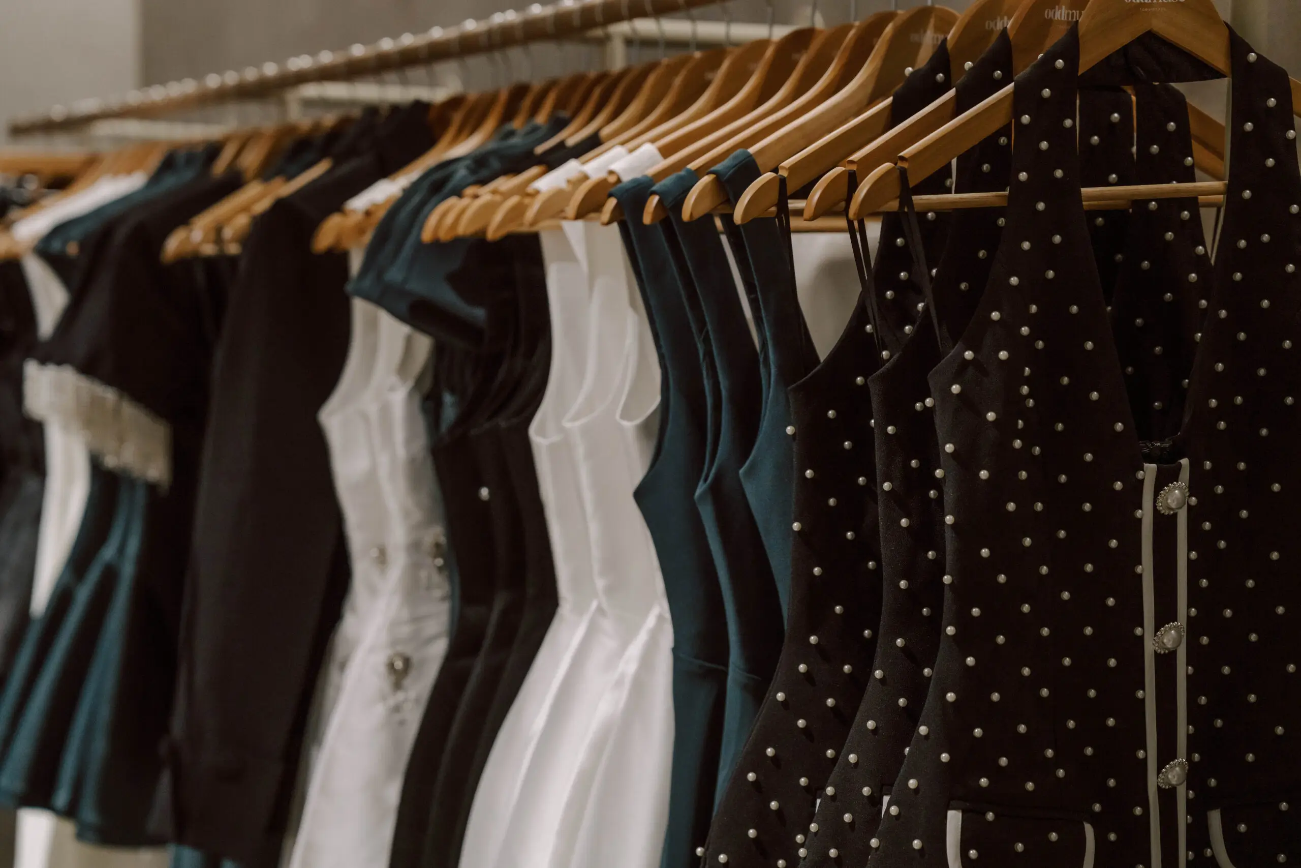 Black, White And Emerald Odd Muse Dresses Displayed On Wooden Hangers