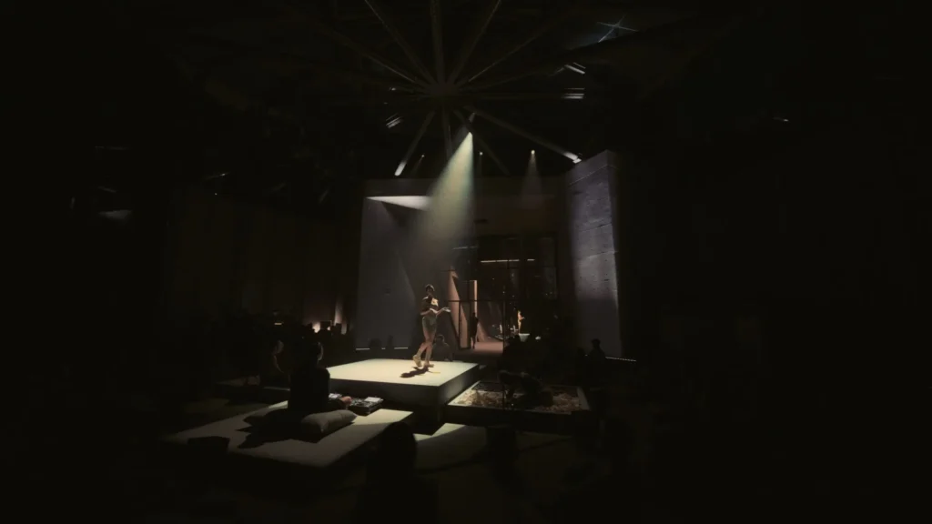 Wide View Of A Dark Shoe Venue With A Performer light On A Central Raise Platform