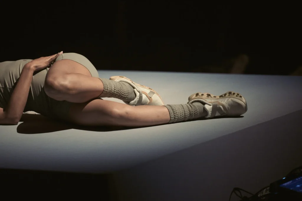 Close-Up Of A Performer’s Leg Wear Neutral Shoe Shoe And Texture Sock On A Lit Platform