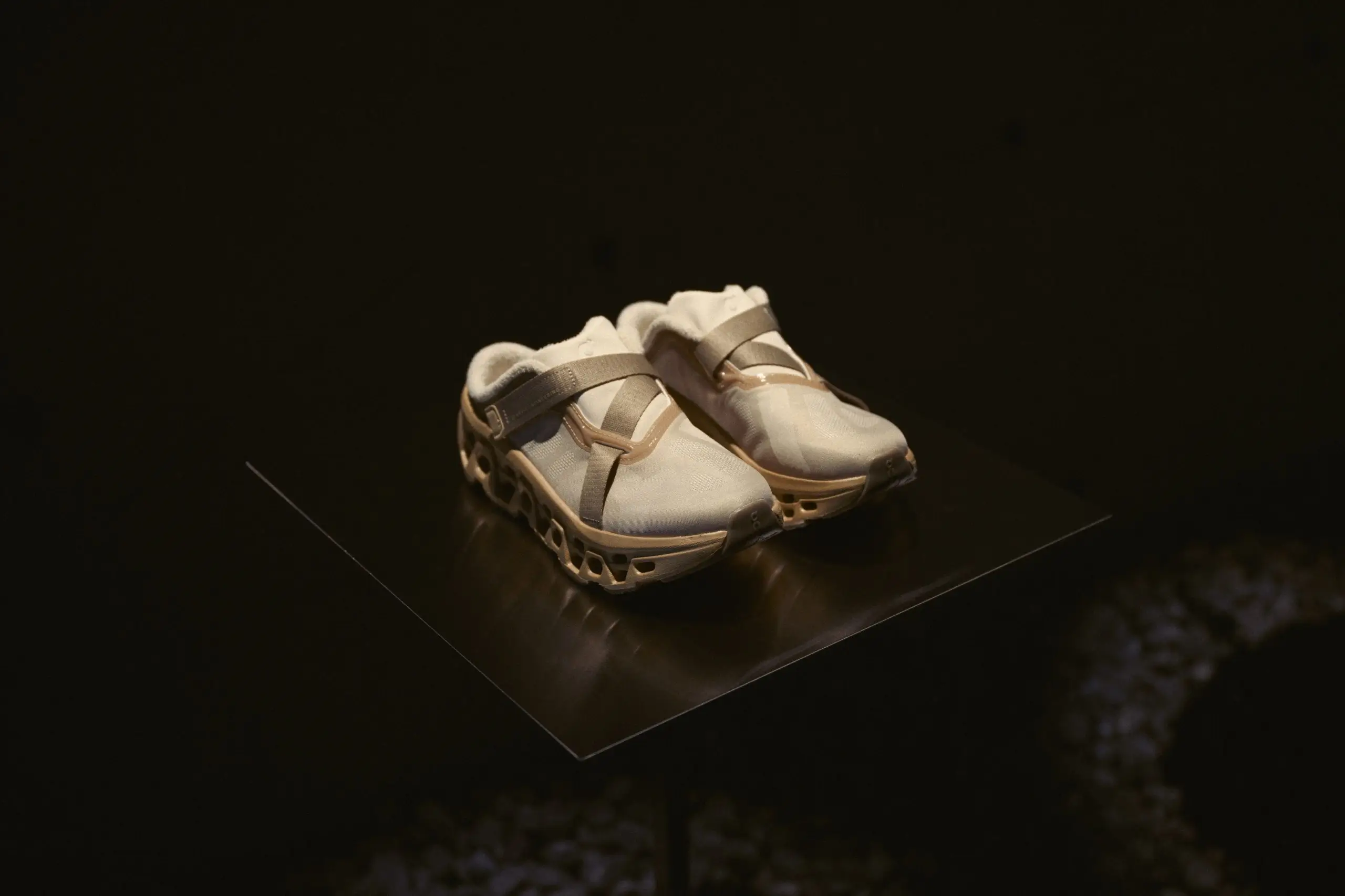 Cream On Performance Shoes Displayed On A Black Pedestal Under A Focused Spotlight