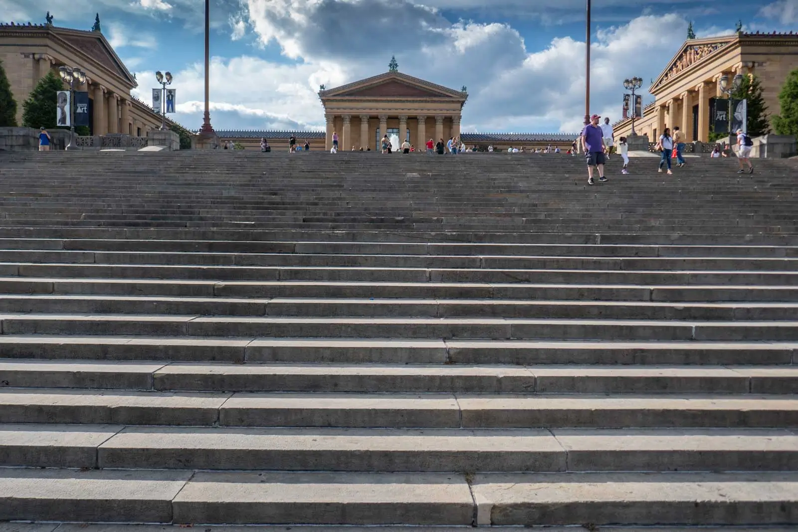 Wide view of the Philadelphia Museum of Art and its monumental stone steps beneath a partly cloudy sky.