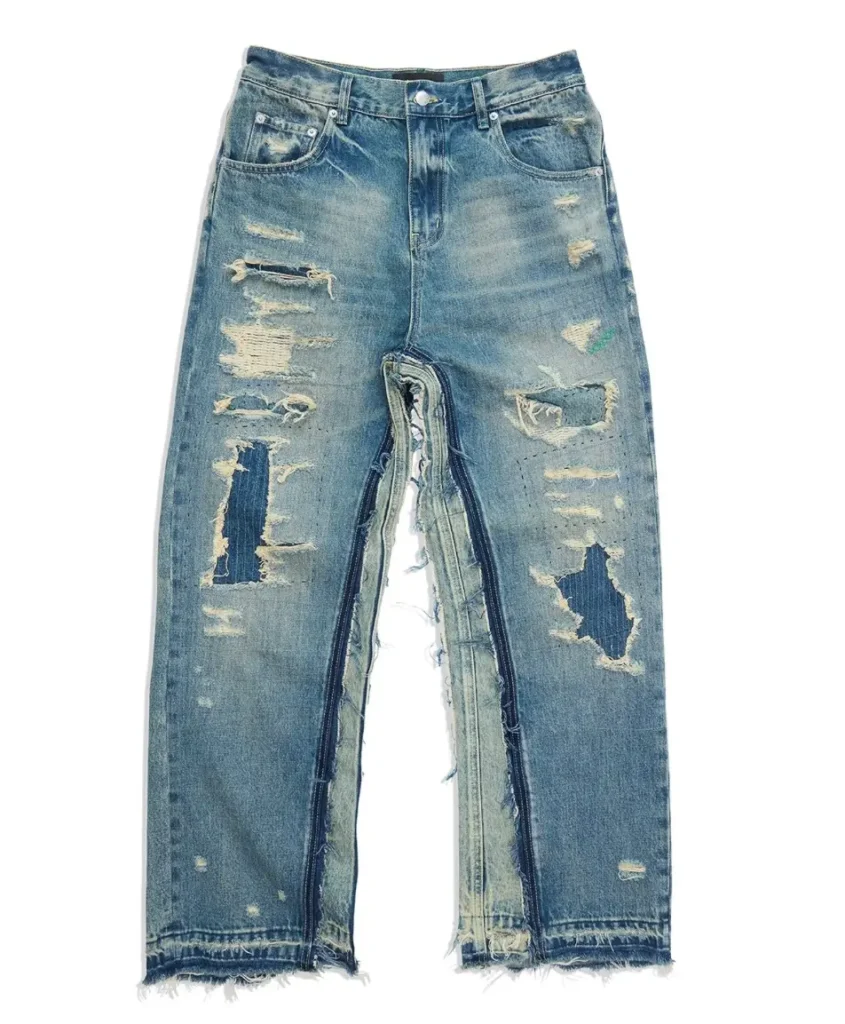 Light-wash distressed wide-leg jeans with heavy abrasions, exposed patchwork, raw hems, repaired panels, and a dramatic open inseam construction