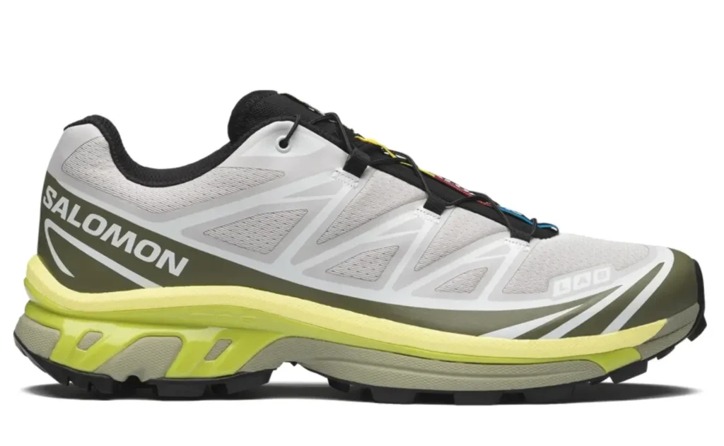 Side profile of the Salomon XT-6 trail running shoe with a white mesh upper, olive overlays, neon yellow cushion, and rugged outsole