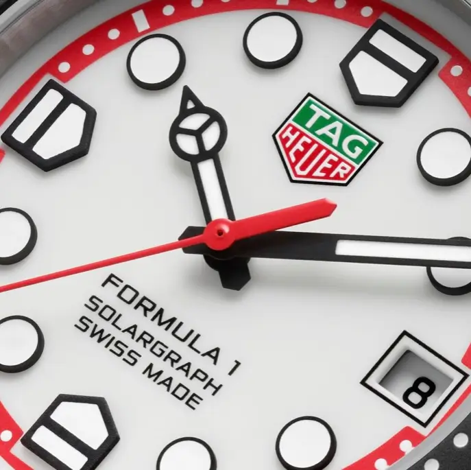 Macro view of the TAG Heuer Formula 1 Solargraph white dial with red accents, raised hour markers, TAG Heuer shield, red seconds hand and date window.