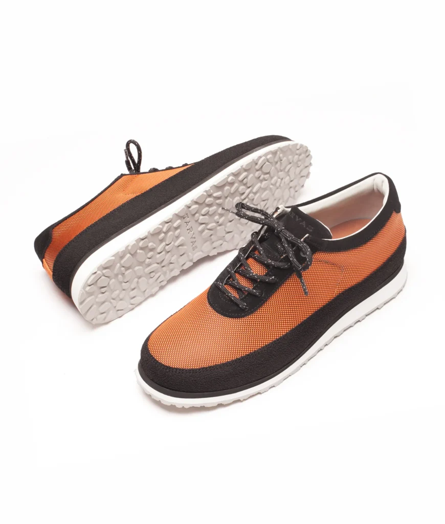 Pair of metallic orange and black sneakers showcasing the textured white outsole and contrasting black overlay