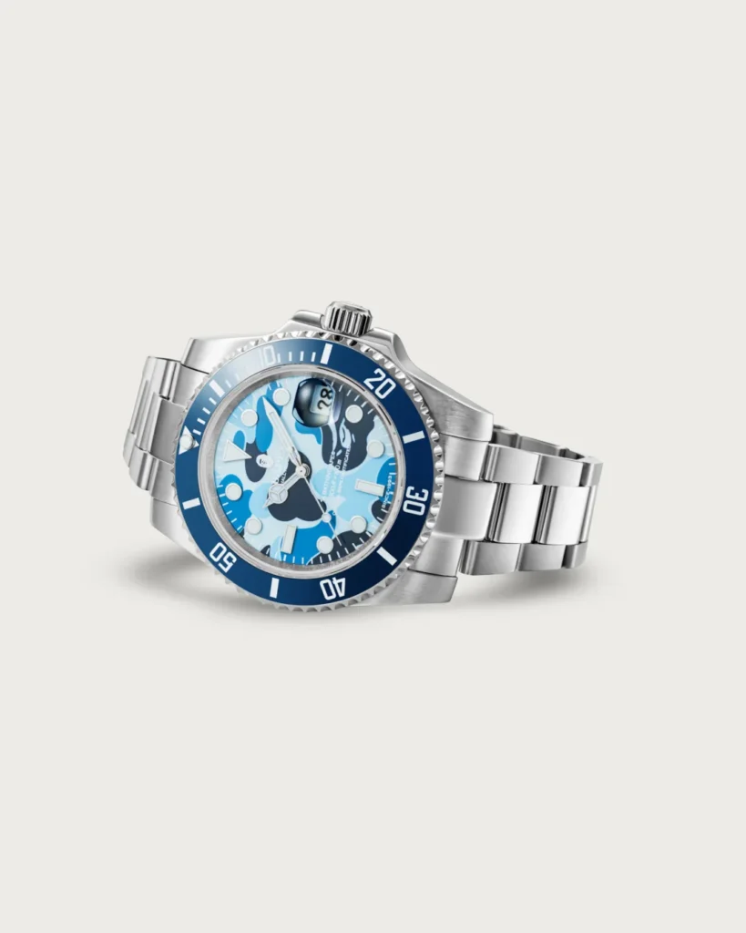 Angled view of the blue BAPEX watch with a blue camouflage dial, dark blue bezel, and stainless steel bracelet