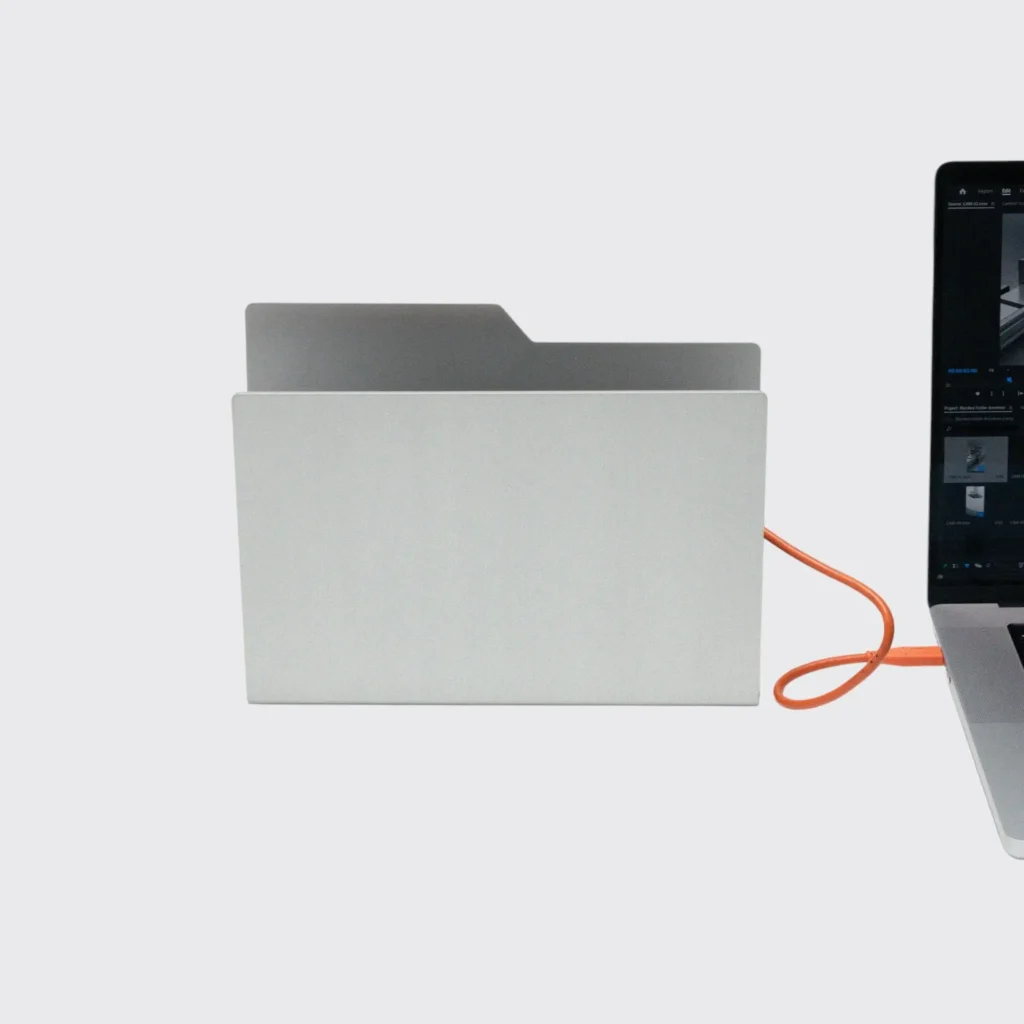 Silver Metal Desktop Folder Beside Laptop Connect With Orange Cable On White Background