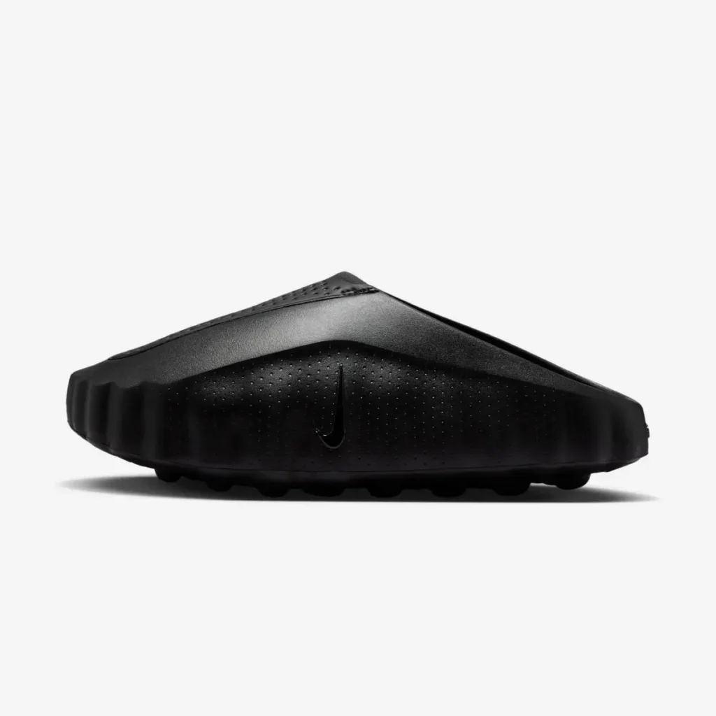 Position lateral profile of a black Nike mule with a sculpted slip-on design, textured upper, perforated sidewall, and rugged traction sole against a white background