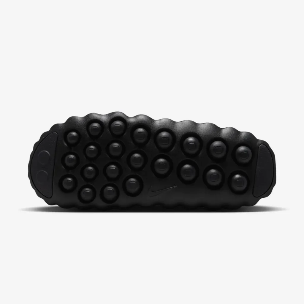 Bottom view of a black Nike mule show a lugged rubber outsole with raised circular traction pods and a small Nike Swoosh at the center