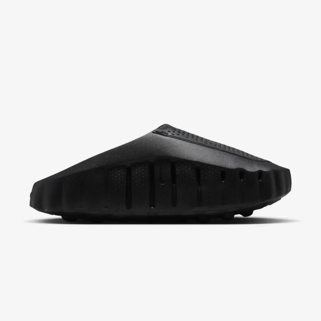 Opposite side profile of a black Nike mule highlighting deep vertical grooves, perforated sidewall detailing, and an angular sculpted sil