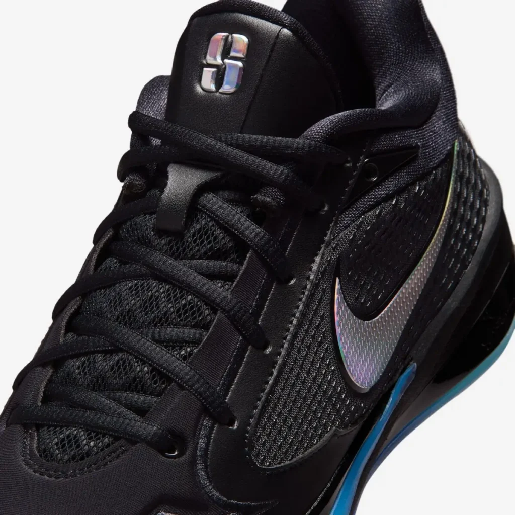 Close-up of the black mesh upper, lacing system, metallic tongue emblem and iridescent Nike Swoosh