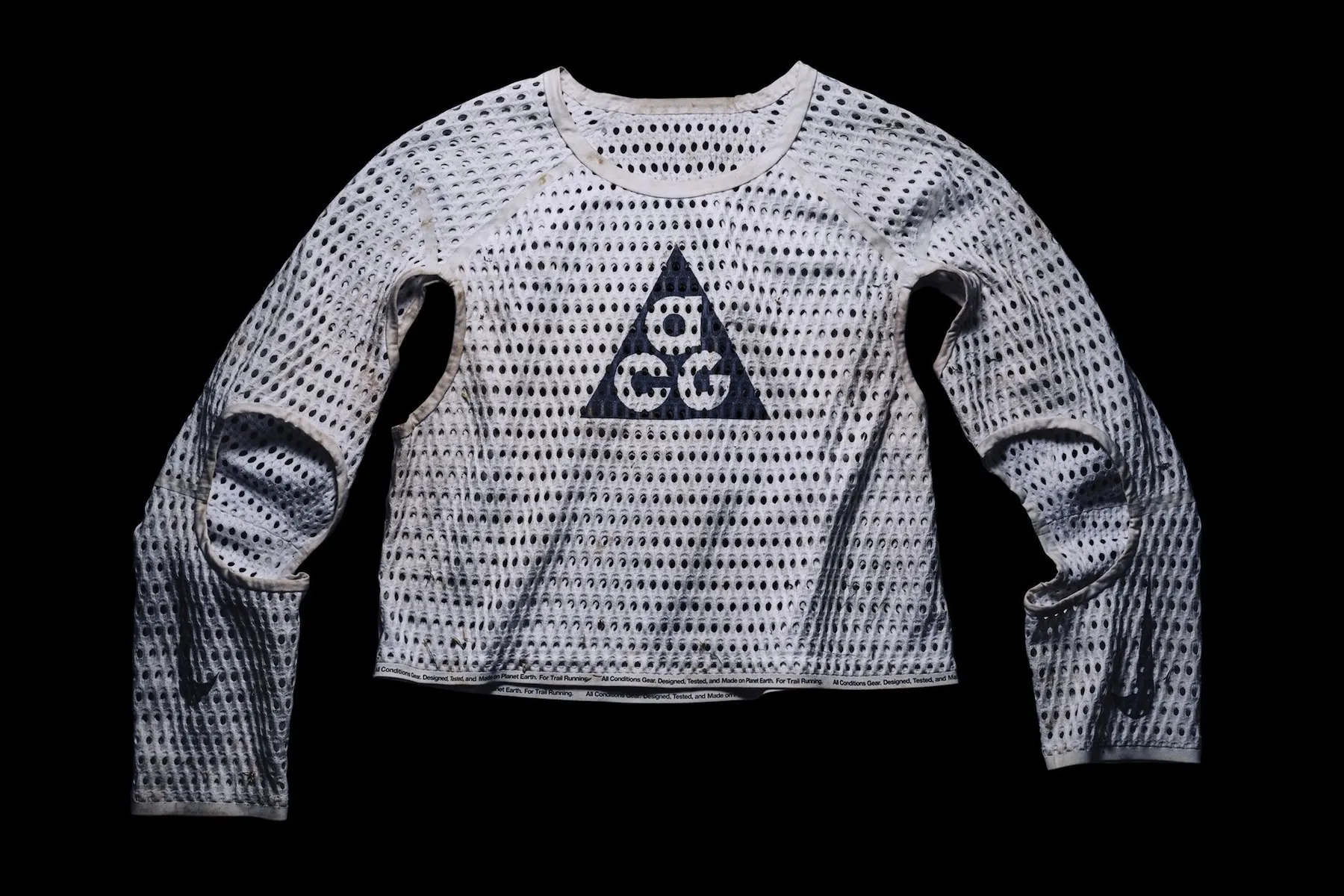White perforated Nike ACG long-sleeve top with triangular logo and cutout panels on a black background