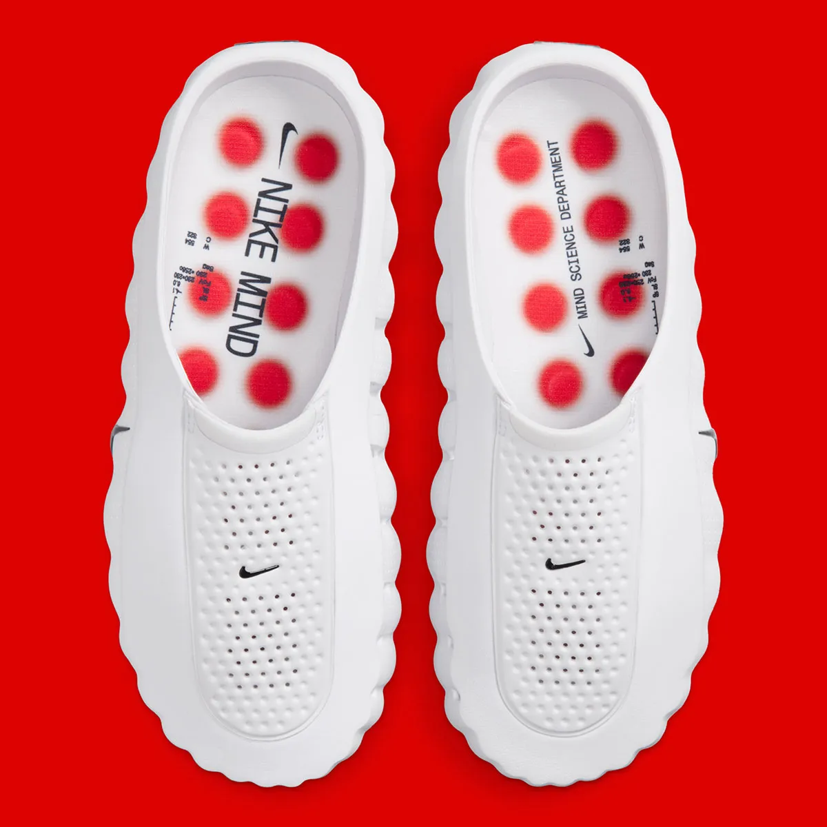 White Nike Mind Slip-On Pair With Perforated Footbeds, Red Circular Cushioning Pods, Black Swooshes, And Mind Science Department Branding On A Red Background