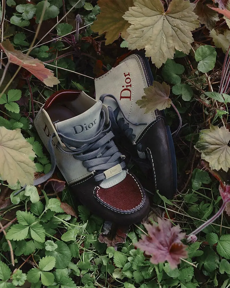 Dior shoes photographed among dense green foliage and autumn leaves.