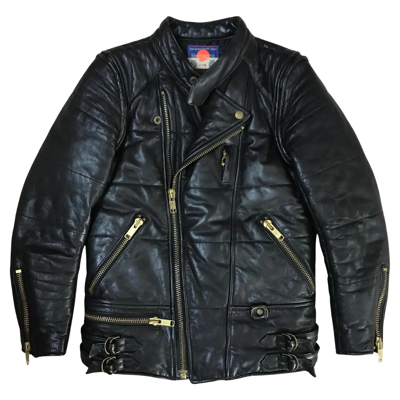 Vintage black leather motorcycle jacket with an asymmetrical zip front, quilted shoulders, brass hardware, multiple zip pockets, waist buckles, and a stand collar.