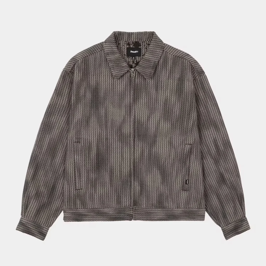 Gray HUF zip-up jacket with a herringbone pattern, pointed collar, long sleeves, and front pockets on a white background