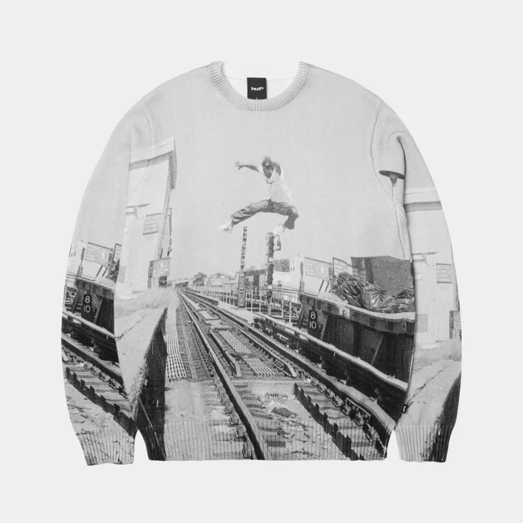 White HUF crewneck sweater printed with a black-and-white train station scene and crouching figure