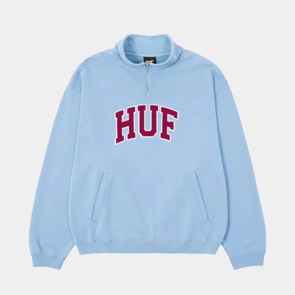 Light blue HUF quarter-zip pullover with burgundy-and-white HUF lettering, kangaroo pockets, and ribbed cuffs on a white