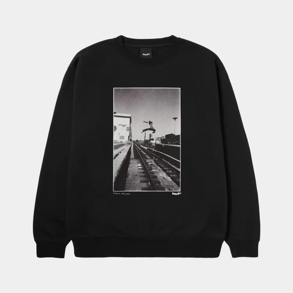Black HUF sweatshirt with a centered black-and-white photo of a skateboarder jumping over railway tracks