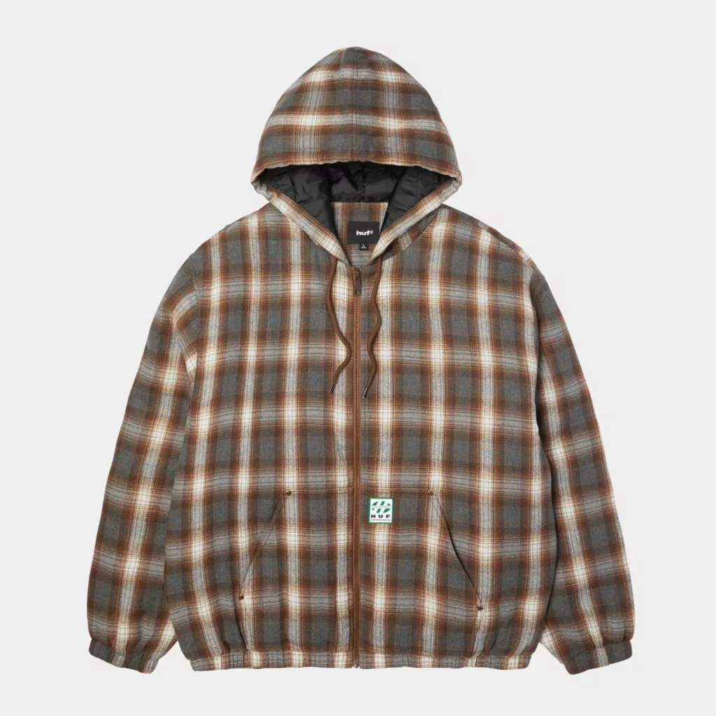 Brown and gray plaid zip-up hooded jacket with black lining and HUF label, displayed against a light gray background