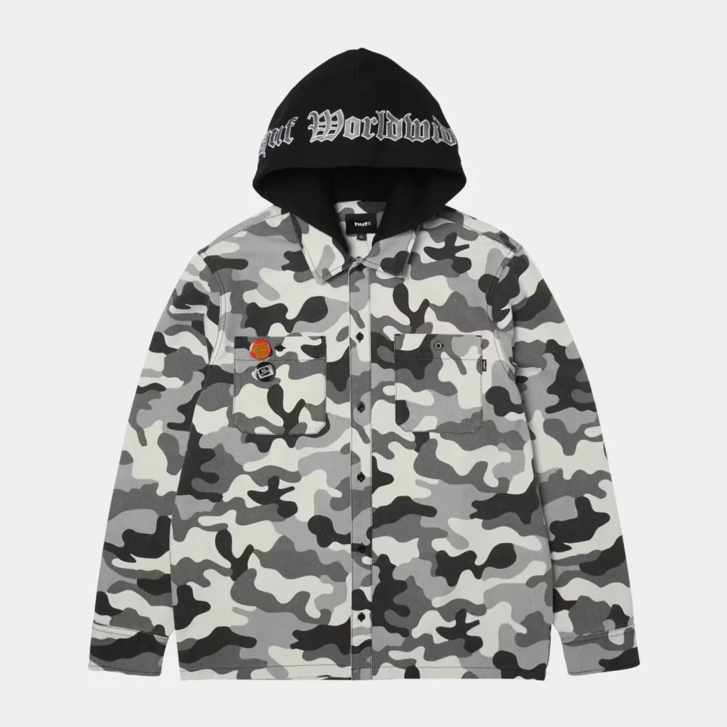 Gray camouflage button-up jacket with chest pockets and pins, displayed beneath a black hood reading “HUF Worldwide”