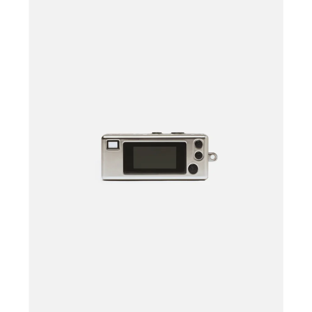Silver mini digital camera with black screen, buttons, and keyring loop, centered against a white background