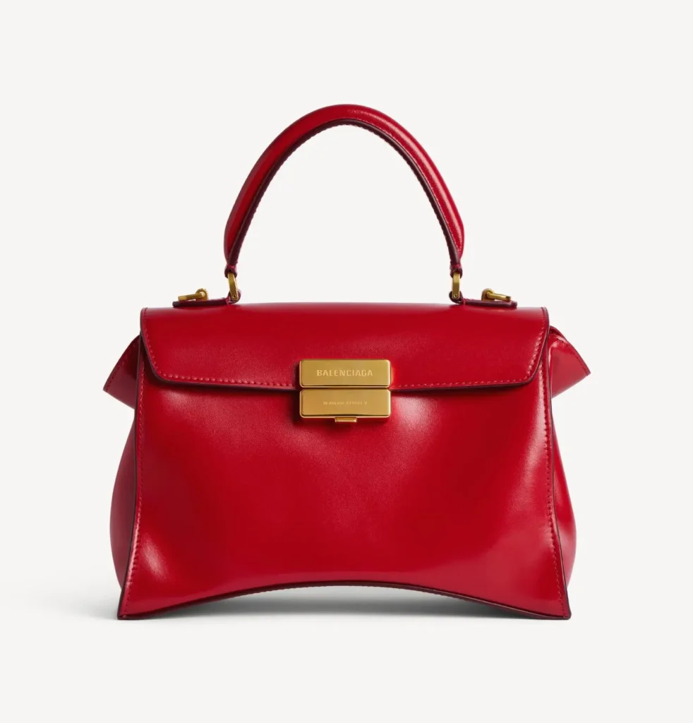 Red leather Balenciaga handbag with a top handle and gold rectangular clasp, centered against a white background