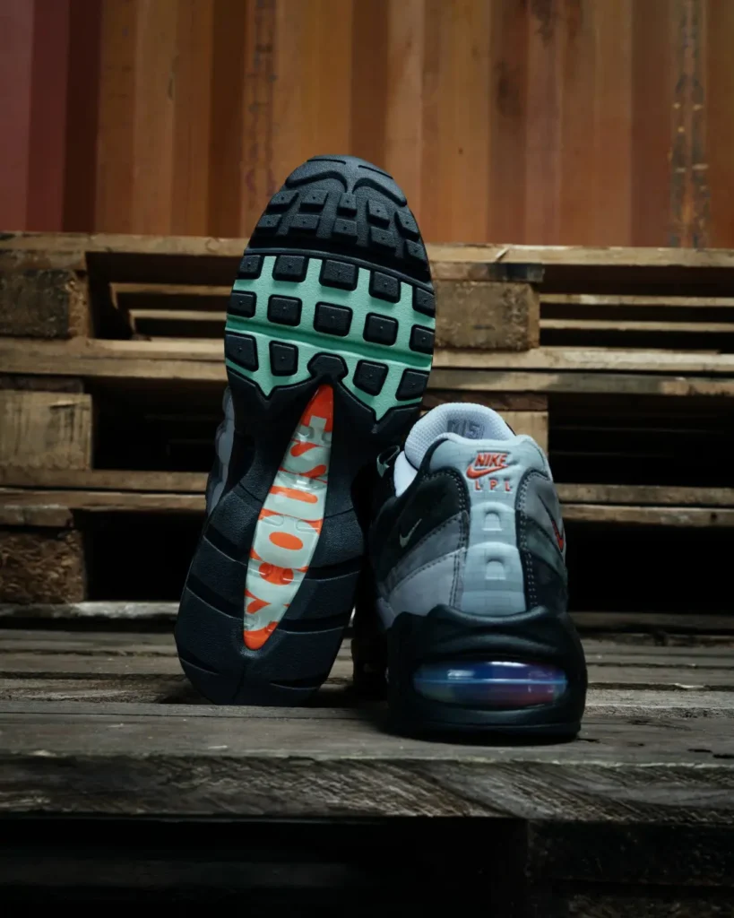 Two Nike shoe on wooden pallets; one shows a black-and-mint sole, the other a gray and black upper with orange branding