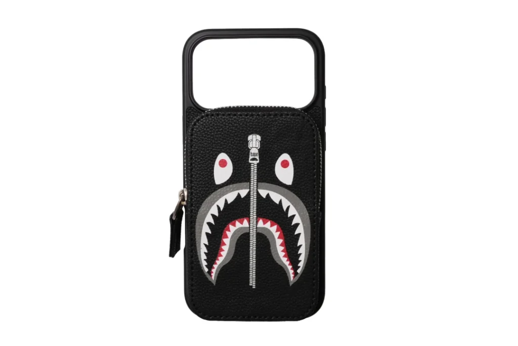 Black leather phone case with a top handle, zipper pocket, and shark-face graphic on a white background