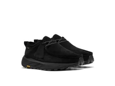 Pair of black suede moccasin-style hiking shoes with laces and rugged Vibram soles on a white background