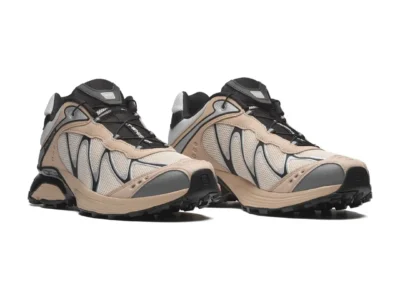 Pair of beige and black Salomon trail shoes with mesh panels and rugged black soles on a white background