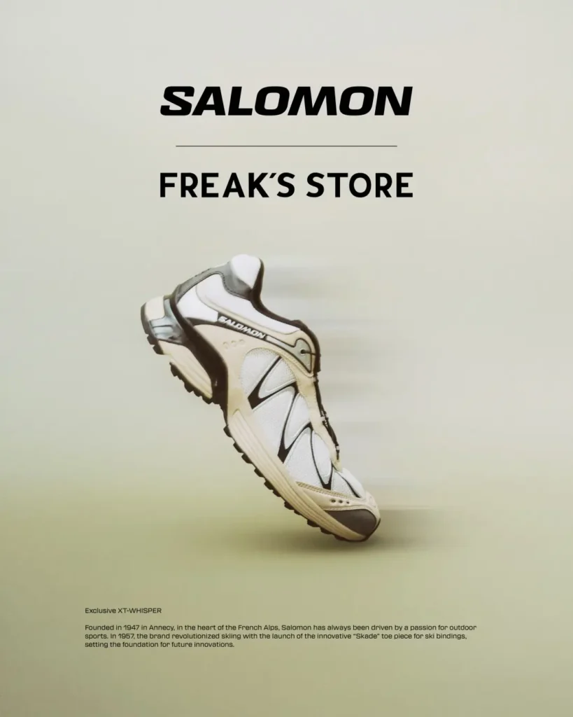 White Salomon sneaker with black accents floats against a pale background beneath bold Salomon branding and text