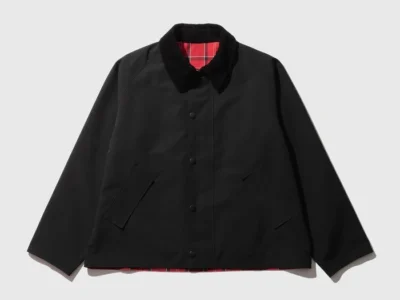 Black jacket with a corduroy collar, red plaid lining, front buttons, and angled welt pockets on a gray background