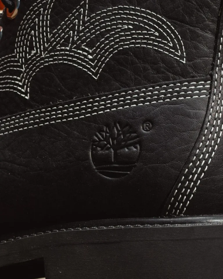 Close-up of a black leather Timberland shoe with white contrast stitching and an embossed tree logo