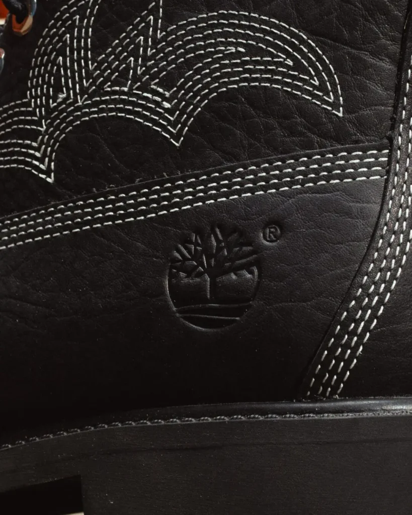 Close-up of a black leather Timberland shoe with white contrast stitching and an embossed tree logo