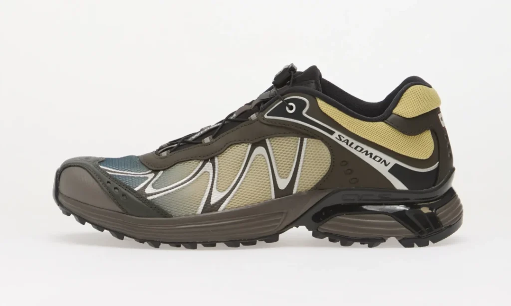Side view of a brown, black, gray and beige Salomon trail shoe with mesh panels and rugged lugged sole on white background