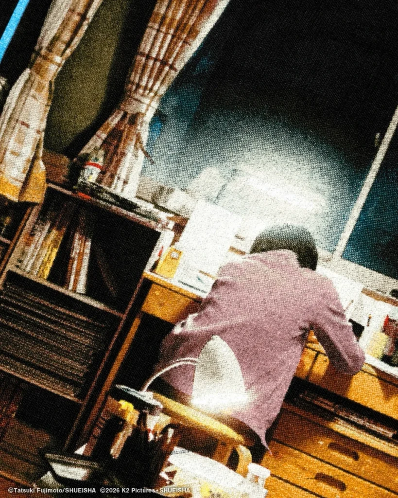 Person in a mauve jacket sits at a desk facing a bright window, with bookshelves and papers around them