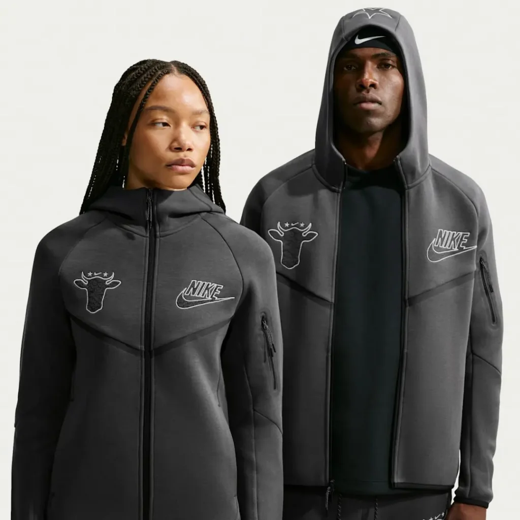 Two models wear dark gray Nike hoodies featuring outlined cow-head graphics and Nike logos against a light background