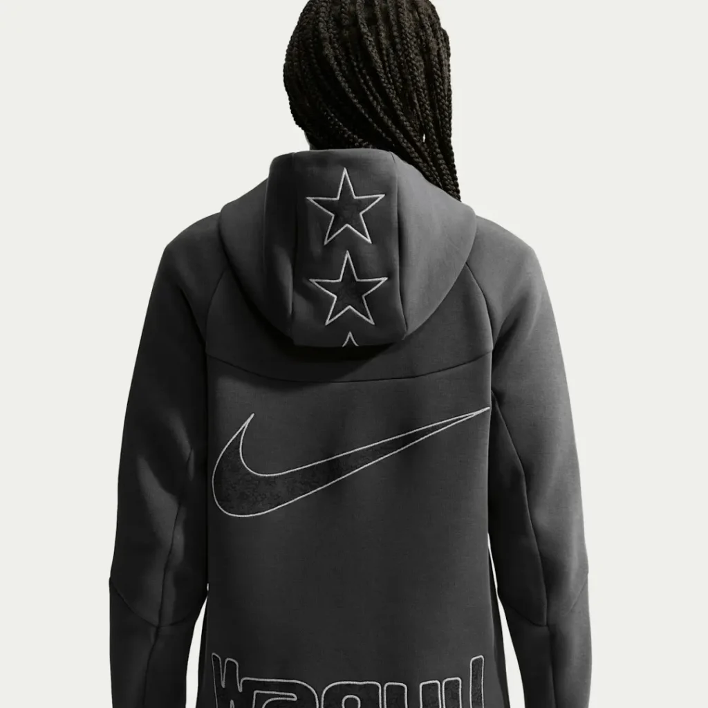 Back view of a person in a black Nike hoodie with outlined stars on the hood and a large swoosh across the back